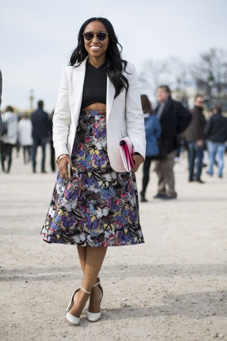 Młoda kobieta we wzorzystej spódnicy midi i białej marynarce damskiej.