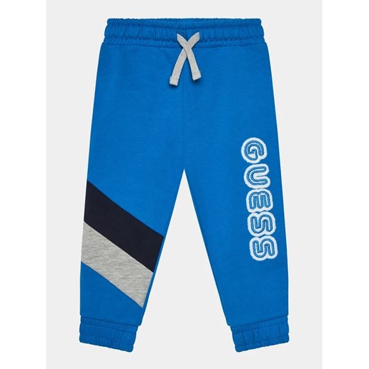 Guess Spodnie dresowe N4RQ11 KA6R4 Niebieski Regular Fit ze sklepu MODIVO w kategorii Spodnie chłopięce - zdjęcie 168481034