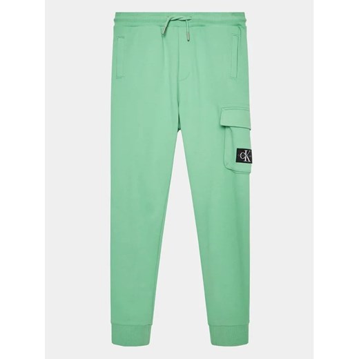 Calvin Klein Jeans Spodnie dresowe Badge Cargo IB0IB01600 Zielony Regular Fit ze sklepu MODIVO w kategorii Spodnie chłopięce - zdjęcie 168496884