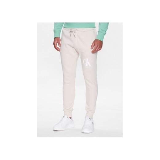 Calvin Klein Jeans Spodnie dresowe J30J322917 Beżowy Regular Fit ze sklepu MODIVO w kategorii Spodnie męskie - zdjęcie 168631291