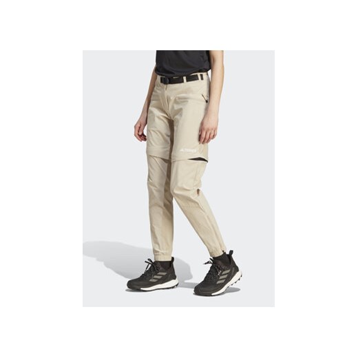 adidas Spodnie dresowe Terrex Utilitas Hiking Zip-Off Tracksuit Bottoms HZ9046 Beżowy Regular Fit ze sklepu MODIVO w kategorii Spodnie męskie - zdjęcie 169340022