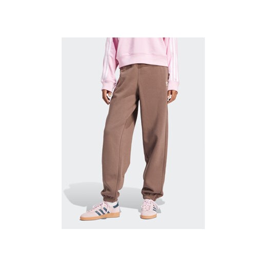 adidas Spodnie dresowe adicolor Essentials IR5974 Brązowy Regular Fit ze sklepu MODIVO w kategorii Spodnie damskie - zdjęcie 169423322