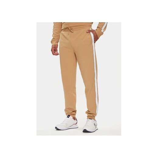 Tommy Hilfiger Spodnie dresowe UM0UM03013 Beżowy Regular Fit ze sklepu MODIVO w kategorii Spodnie męskie - zdjęcie 170468500
