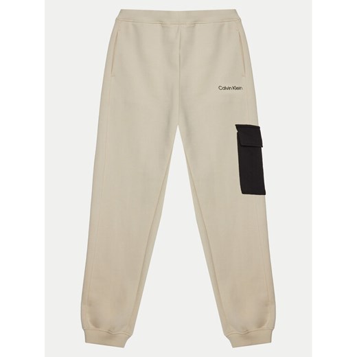 Calvin Klein Jeans Spodnie dresowe IB0IB02349 Écru Relaxed Fit ze sklepu MODIVO w kategorii Spodnie chłopięce - zdjęcie 182684464