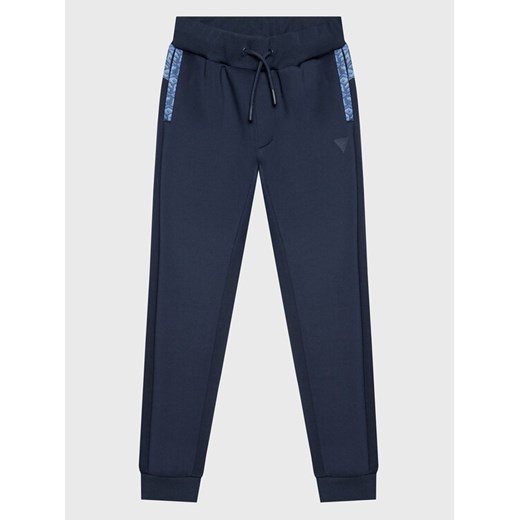 Guess Spodnie dresowe L3RQ15 JR06W Niebieski Relaxed Fit ze sklepu MODIVO w kategorii Spodnie chłopięce - zdjęcie 182695201