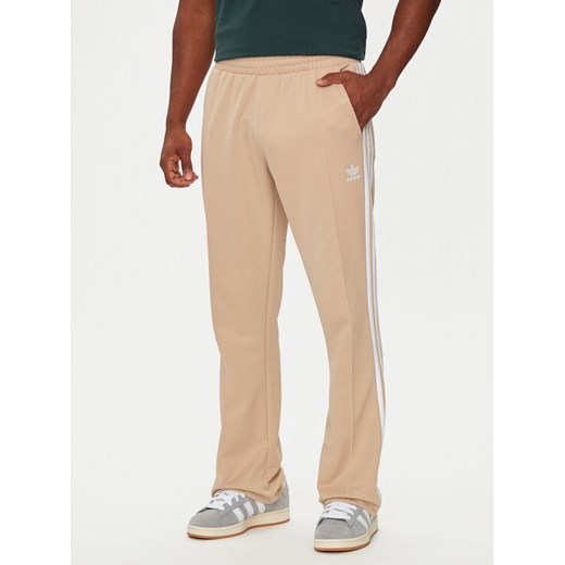 adidas Spodnie dresowe adicolor 70's IX5221 Beżowy Regular Fit ze sklepu MODIVO w kategorii Spodnie męskie - zdjęcie 182726682