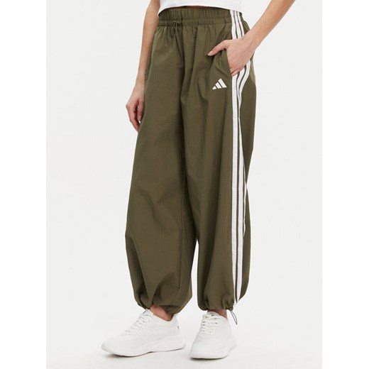 adidas Spodnie dresowe Essentials 3-Stripes JE1308 Zielony Loose Fit ze sklepu MODIVO w kategorii Spodnie damskie - zdjęcie 182742450