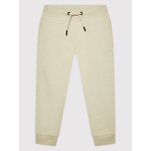 Guess Spodnie dresowe L2YQ46 KAIJ1 Beżowy Regular Fit ze sklepu MODIVO w kategorii Spodnie chłopięce - zdjęcie 182744780