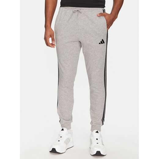 adidas Spodnie dresowe Essential 3-Stripes JE6346 Szary Regular Fit ze sklepu MODIVO w kategorii Spodnie męskie - zdjęcie 182764693
