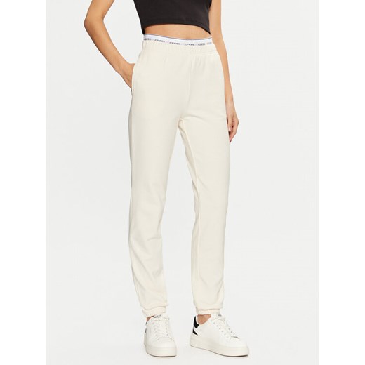 Guess Spodnie dresowe O5RB01 KCO31 Écru Regular Fit ze sklepu MODIVO w kategorii Spodnie damskie - zdjęcie 184187371