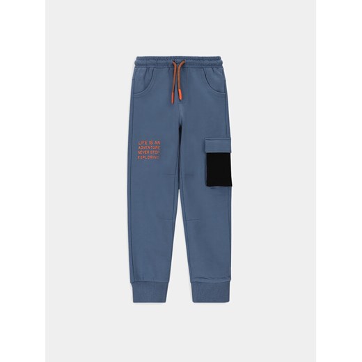 Coccodrillo Spodnie dresowe WC4120102DEK Niebieski Slim Fit ze sklepu MODIVO w kategorii Spodnie chłopięce - zdjęcie 184214463