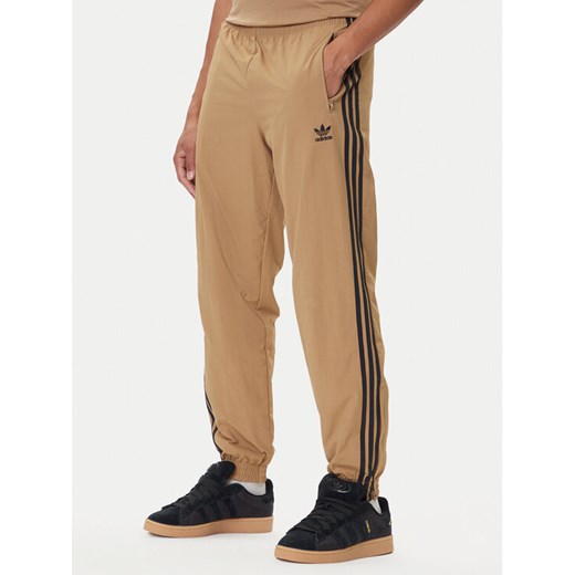 adidas Spodnie dresowe adicolor Woven Firebird JY1339 Beżowy Regular Fit ze sklepu MODIVO w kategorii Spodnie męskie - zdjęcie 185415911