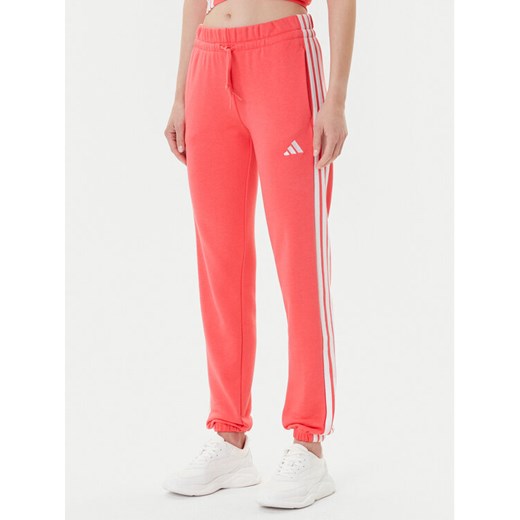 adidas Spodnie dresowe Essentials 3-Stripes KE4387 Koralowy Regular Fit ze sklepu MODIVO w kategorii Spodnie damskie - zdjęcie 185913812