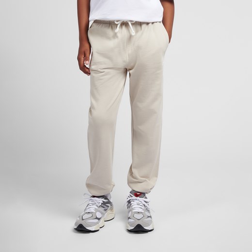 Spodnie dziecięce New Balance LAKB0060TWF – beżowe ze sklepu New Balance Poland w kategorii Spodnie męskie - zdjęcie 186126022