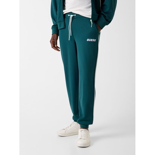 Guess Spodnie materiałowe 180419 Zielony Regular Fit ze sklepu MODIVO w kategorii Spodnie męskie - zdjęcie 188020530