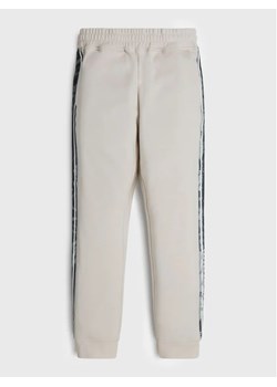 Guess Spodnie dresowe L2YQ18 KB6R2 Beżowy Regular Fit ze sklepu MODIVO w kategorii Spodnie chłopięce - zdjęcie 168377373