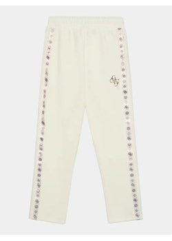 Guess Spodnie dresowe J3BQ12 KBYO0 Écru Relaxed Fit ze sklepu MODIVO w kategorii Spodnie dziewczęce - zdjęcie 168411370