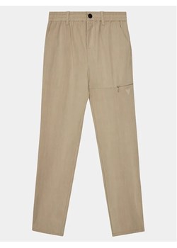 Guess Spodnie materiałowe Long L4RB00 WFKR0 Beżowy Regular Fit ze sklepu MODIVO w kategorii Spodnie chłopięce - zdjęcie 168430212