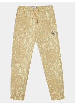 Calvin Klein Jeans Spodnie dresowe Second Skin IB0IB01932 Beżowy Relaxed Fit ze sklepu MODIVO w kategorii Spodnie chłopięce - zdjęcie 168467172