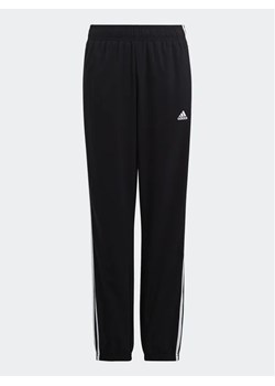 adidas Spodnie dresowe Essentials 3-Stripes Woven Tracksuit Bottoms HR6334 Czarny Slim Fit ze sklepu MODIVO w kategorii Spodnie chłopięce - zdjęcie 168478702