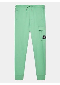 Calvin Klein Jeans Spodnie dresowe Badge Cargo IB0IB01600 Zielony Regular Fit ze sklepu MODIVO w kategorii Spodnie chłopięce - zdjęcie 168496884