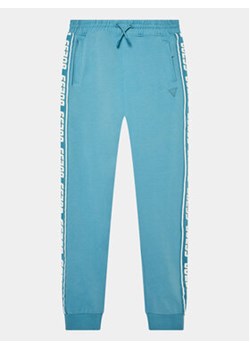 Guess Spodnie dresowe L2YQ48 K6ZS1 Niebieski Regular Fit ze sklepu MODIVO w kategorii Spodnie chłopięce - zdjęcie 168542681