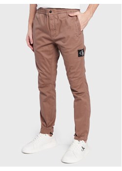 Calvin Klein Jeans Spodnie materiałowe J30J322041 Brązowy Regular Fit ze sklepu MODIVO w kategorii Spodnie męskie - zdjęcie 168600604