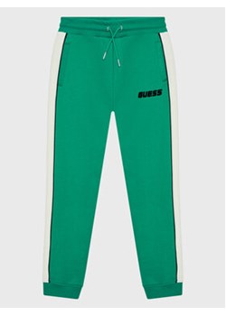 Guess Spodnie dresowe L2BQ19 KBGQ2 Zielony Regular Fit ze sklepu MODIVO w kategorii Spodnie chłopięce - zdjęcie 168604432
