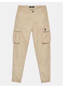 Guess Spodnie materiałowe L3BB02 WE1L0 Beżowy Regular Fit ze sklepu MODIVO w kategorii Spodnie chłopięce - zdjęcie 168611091