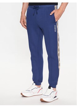Guess Spodnie dresowe Mickey Z2YB09 KB3P2 Niebieski Regular Fit ze sklepu MODIVO w kategorii Spodnie męskie - zdjęcie 168621600