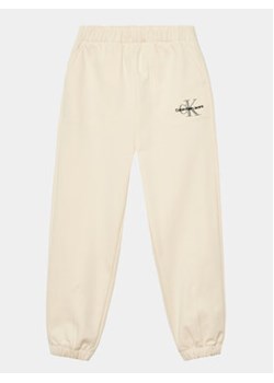 Calvin Klein Jeans Spodnie dresowe Monogram IG0IG02094 Écru Regular Fit ze sklepu MODIVO w kategorii Spodnie dziewczęce - zdjęcie 168627560
