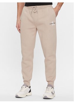 Calvin Klein Jeans Spodnie dresowe Monologo J30J324685 Beżowy Regular Fit ze sklepu MODIVO w kategorii Spodnie męskie - zdjęcie 168671134