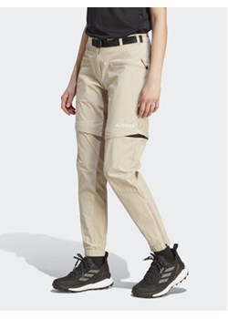 adidas Spodnie dresowe Terrex Utilitas Hiking Zip-Off Tracksuit Bottoms HZ9046 Beżowy Regular Fit ze sklepu MODIVO w kategorii Spodnie męskie - zdjęcie 169340022