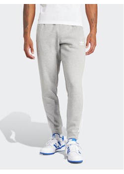 adidas Spodnie dresowe adicolor 3-Stripes IM9318 Szary Slim Fit ze sklepu MODIVO w kategorii Spodnie męskie - zdjęcie 169417930