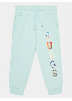 Guess Spodnie dresowe N4GQ11 KA6R3 Niebieski Regular Fit ze sklepu MODIVO w kategorii Spodnie chłopięce - zdjęcie 170236982