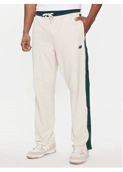 New Balance Spodnie dresowe Greatest Hits MP41504 Beżowy Regular Fit ze sklepu MODIVO w kategorii Spodnie męskie - zdjęcie 171211830