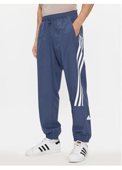 adidas Spodnie dresowe Future Icons 3-Stripes IR9239 Niebieski Slim Fit ze sklepu MODIVO w kategorii Spodnie męskie - zdjęcie 171992512