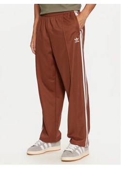 adidas Spodnie dresowe adicolor Firebird IZ2476 Brązowy Baggy Fit ze sklepu MODIVO w kategorii Spodnie męskie - zdjęcie 176875493