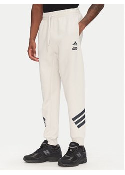 adidas Spodnie dresowe Star Wars The Mandalorian™ JI5723 Beżowy Regular Fit ze sklepu MODIVO w kategorii Spodnie męskie - zdjęcie 180402003