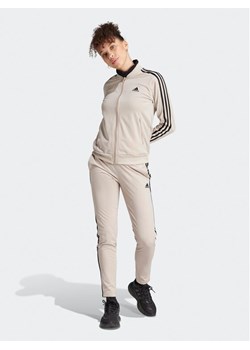 adidas Dres Essentials 3-Stripes IJ8786 Beżowy Slim Fit ze sklepu MODIVO w kategorii Dresy damskie - zdjęcie 181044632