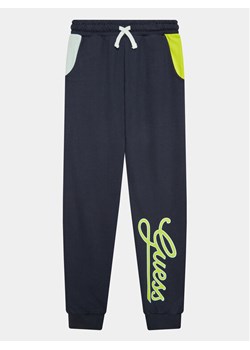 Guess Spodnie dresowe L3YQ34 KA6R3 Granatowy Relaxed Fit ze sklepu MODIVO w kategorii Spodnie chłopięce - zdjęcie 181046522