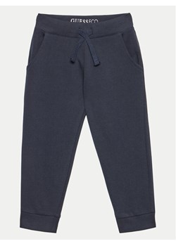 Guess Spodnie dresowe N93Q17 KAUG0 Granatowy Relaxed Fit ze sklepu MODIVO w kategorii Spodnie chłopięce - zdjęcie 181088103