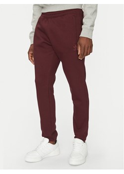 adidas Spodnie dresowe Trefoil Essentials JD2420 Bordowy Slim Fit ze sklepu MODIVO w kategorii Spodnie męskie - zdjęcie 181096431