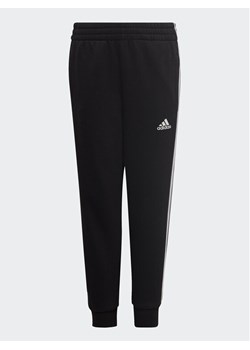 adidas Spodnie dresowe adidas Essential 3-Stripes Joggers H65796 Czarny Regular Fit ze sklepu MODIVO w kategorii Spodnie chłopięce - zdjęcie 181119881