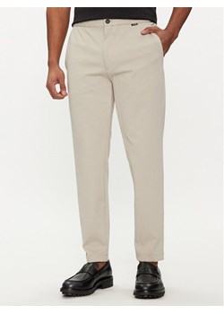 Calvin Klein Spodnie materiałowe K10K113647 Beżowy Comfort Fit ze sklepu MODIVO w kategorii Spodnie męskie - zdjęcie 181132053