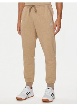 adidas Spodnie dresowe Seasonal Essentials IY6606 Beżowy Regular Fit ze sklepu MODIVO w kategorii Spodnie męskie - zdjęcie 181182552
