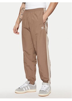 adidas Spodnie dresowe adicolor Firebird JP1024 Beżowy Regular Fit ze sklepu MODIVO w kategorii Spodnie męskie - zdjęcie 182595640