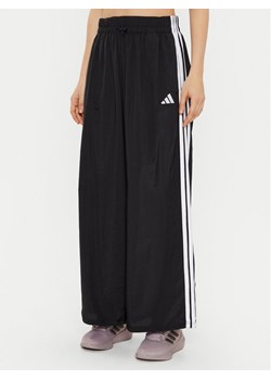 adidas Spodnie dresowe Essentials 3-Stripes JE1306 Czarny Loose Fit ze sklepu MODIVO w kategorii Spodnie damskie - zdjęcie 182613080
