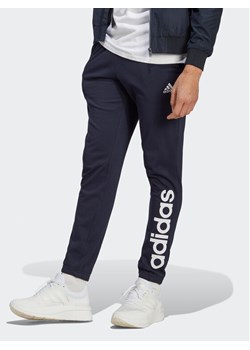 adidas Spodnie dresowe Essentials IC0056 Granatowy Regular Fit ze sklepu MODIVO w kategorii Spodnie męskie - zdjęcie 182636483