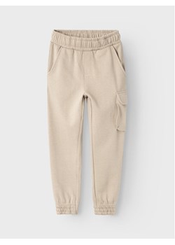 NAME IT Spodnie dresowe Varonto 13225029 Beżowy Regular Fit ze sklepu MODIVO w kategorii Spodnie chłopięce - zdjęcie 182664120